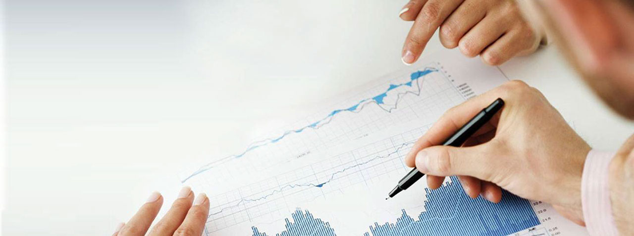 Close-up of the hands of two women pointing at a graph and one man's hand holding a pen ready to markup the report.